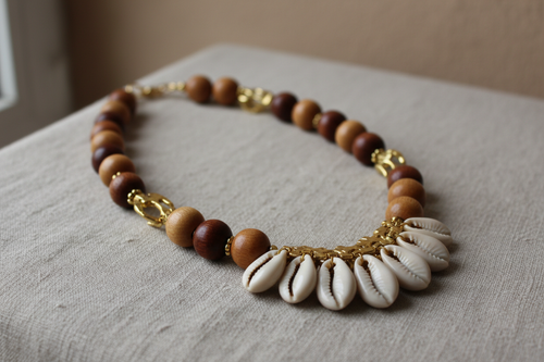 Ce collier artisanal gabonais est une pièce authentique inspirée des traditions africaines. Fabriqué à la main, il associe des perles en bois naturel, des éléments dorés et de véritables coquillages cauris, symboles de protection et de prospérité. Son design chaleureux et ancestral en fait un bijou unique, idéal pour sublimer une tenue traditionnelle ou moderne tout en affirmant une forte identité culturelle africaine.